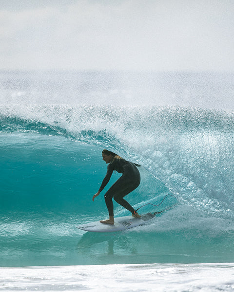 Person surfing on a large wave in clear blue water
