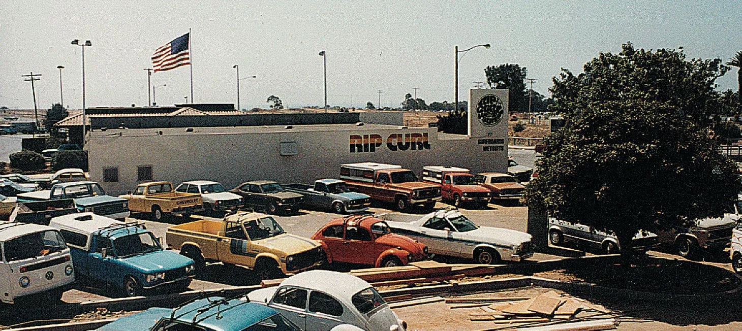 Vintage cars parked outside a building with 'Rip Curl' branding.