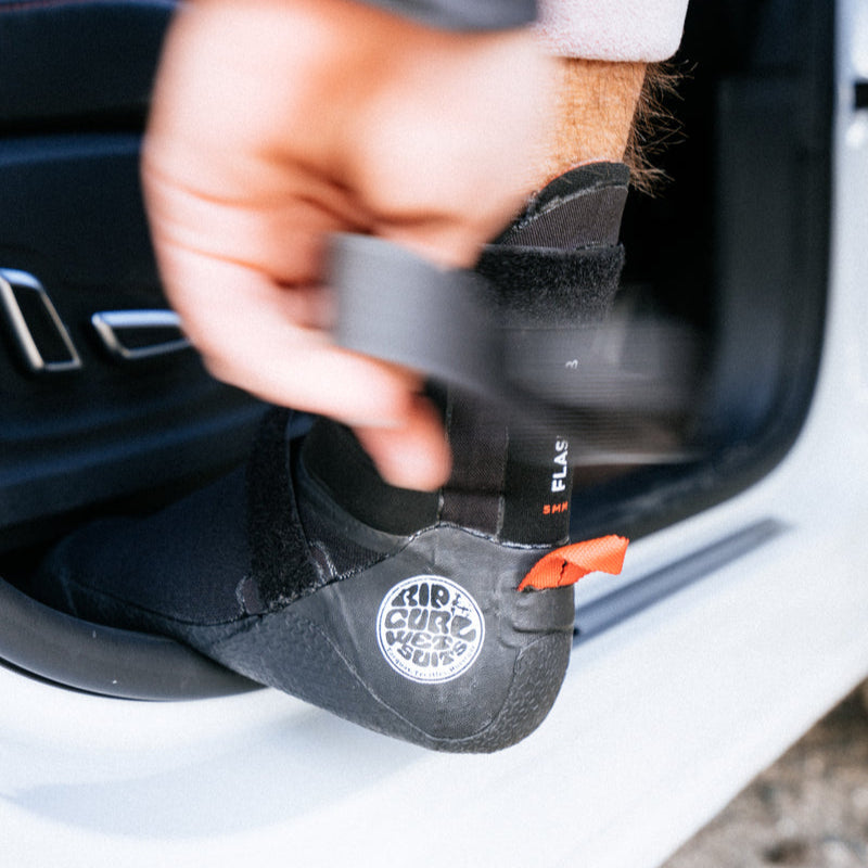 Person wearing black climbing shoes with a visible brand logo, getting into a car.