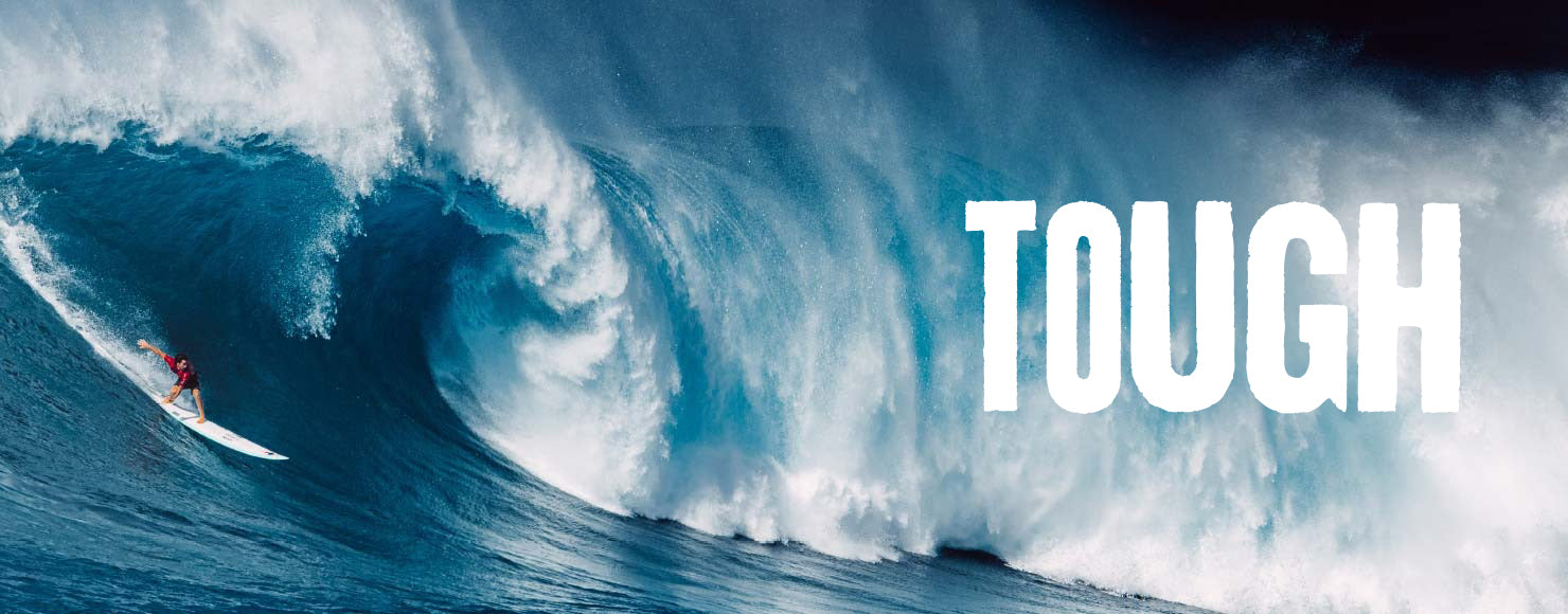 Surfer riding a large wave with the word 'TOUGH' displayed
