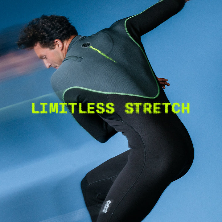 A man in a black full-body wetsuit with bright green trim and the words 'LIMITLESS STRETCH' across the center, posed against a blue background.