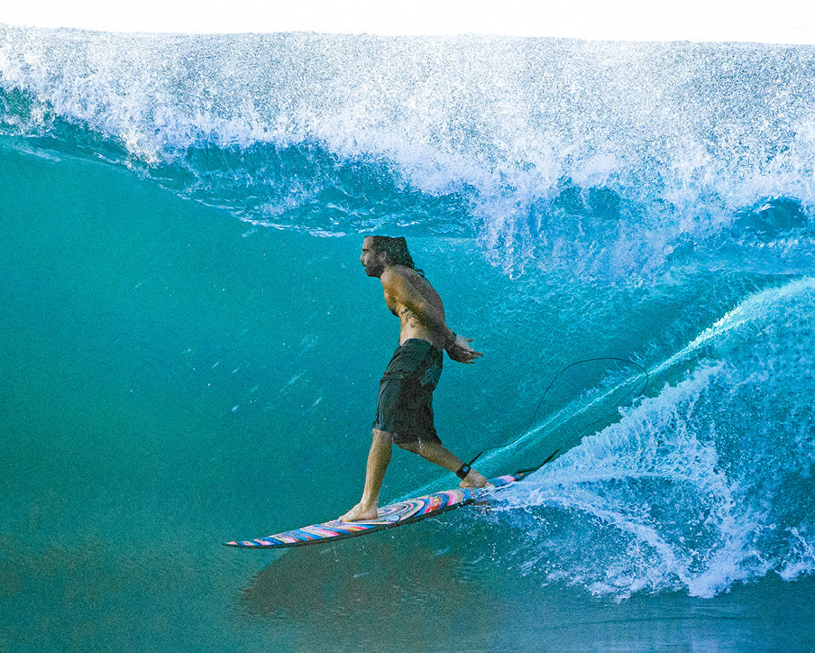 Person surfing on a large wave in clear blue water