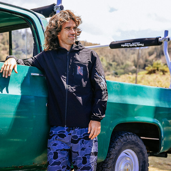 Man leaning against a green truck with a scenic background