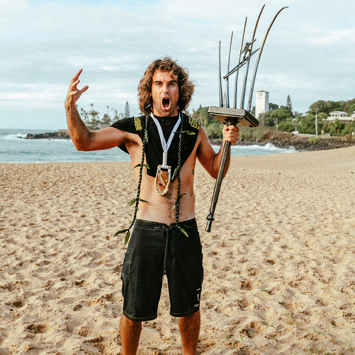 Man on a beach holding a trophy and making a triumphant gesture