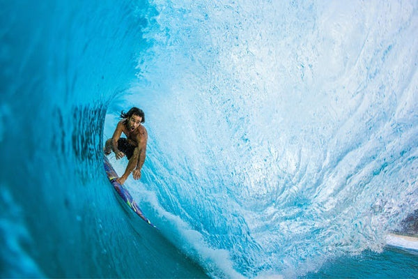 Surfer riding a large wave in crystal blue water