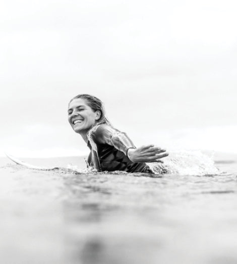 Person in a wetsuit sitting in water with a white background