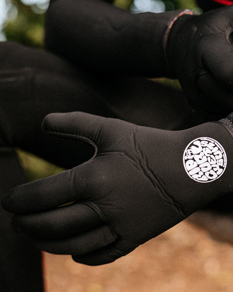 Black gloves with a logo on the back, worn by a person outdoors.